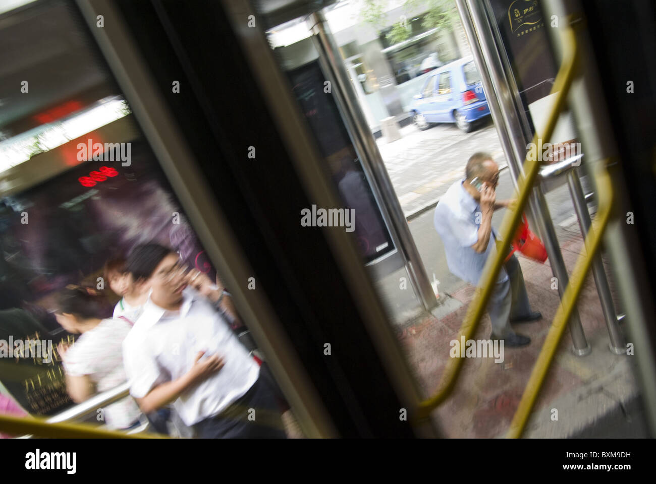 old man talking on cellphone photographed through doors of a public bus,beijing,china Stock Photo