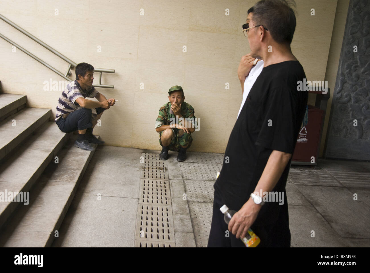 men, one in military uniform, smoking in an underpass,beijing,china Stock Photo