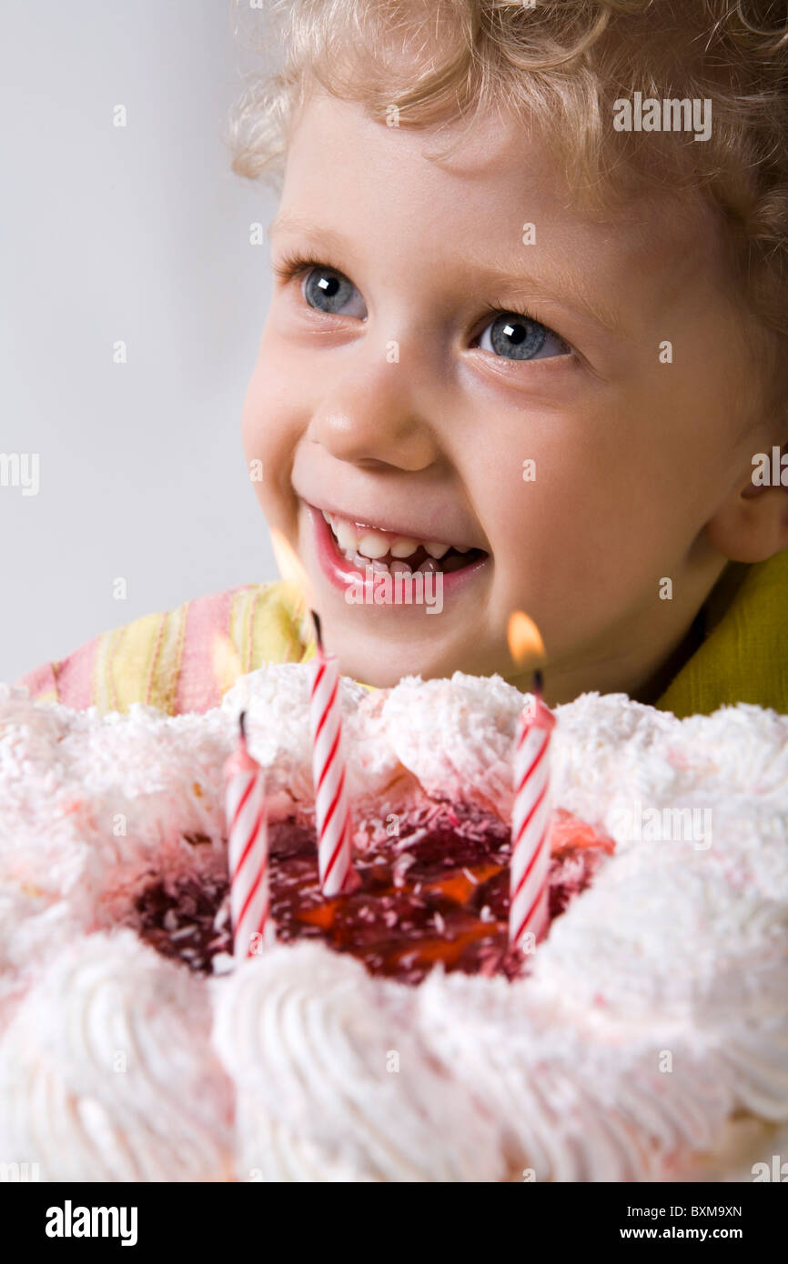Happy curly blond boy with birthday cake going to blow out the candles