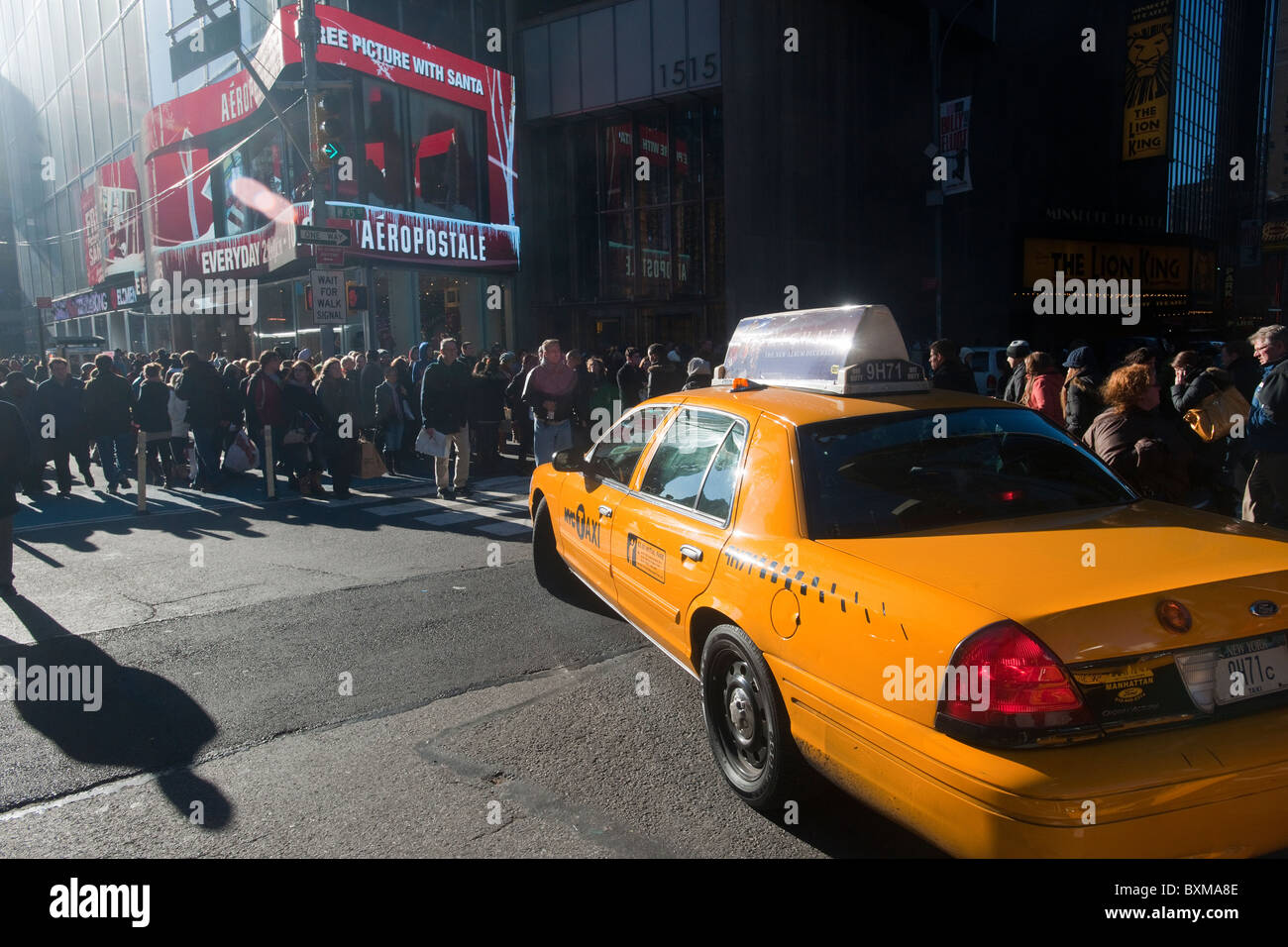 A taxi attempts to turn while a mass of pedestrians maneuvers through the crowded sidewalks and streets in Times Square in NY Stock Photo
