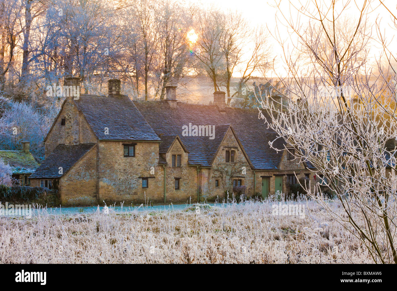 The sun setting on hoar frost on Arlington Row and Rack Isle in the Cotswold village of Bibury, Gloucestershire UK Stock Photo