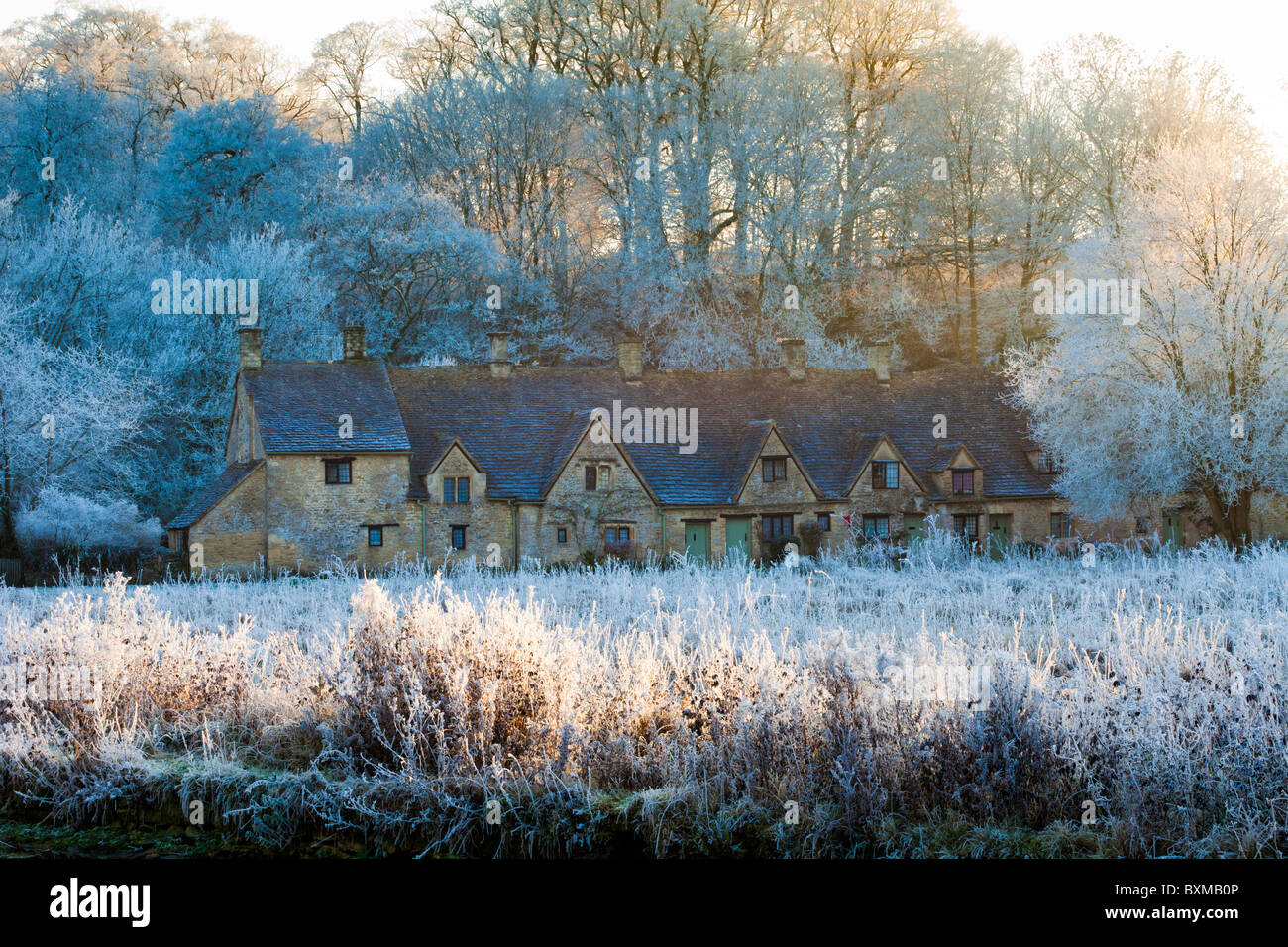 The sun setting on hoar frost on Arlington Row and Rack Isle in the Cotswold village of Bibury, Gloucestershire Stock Photo