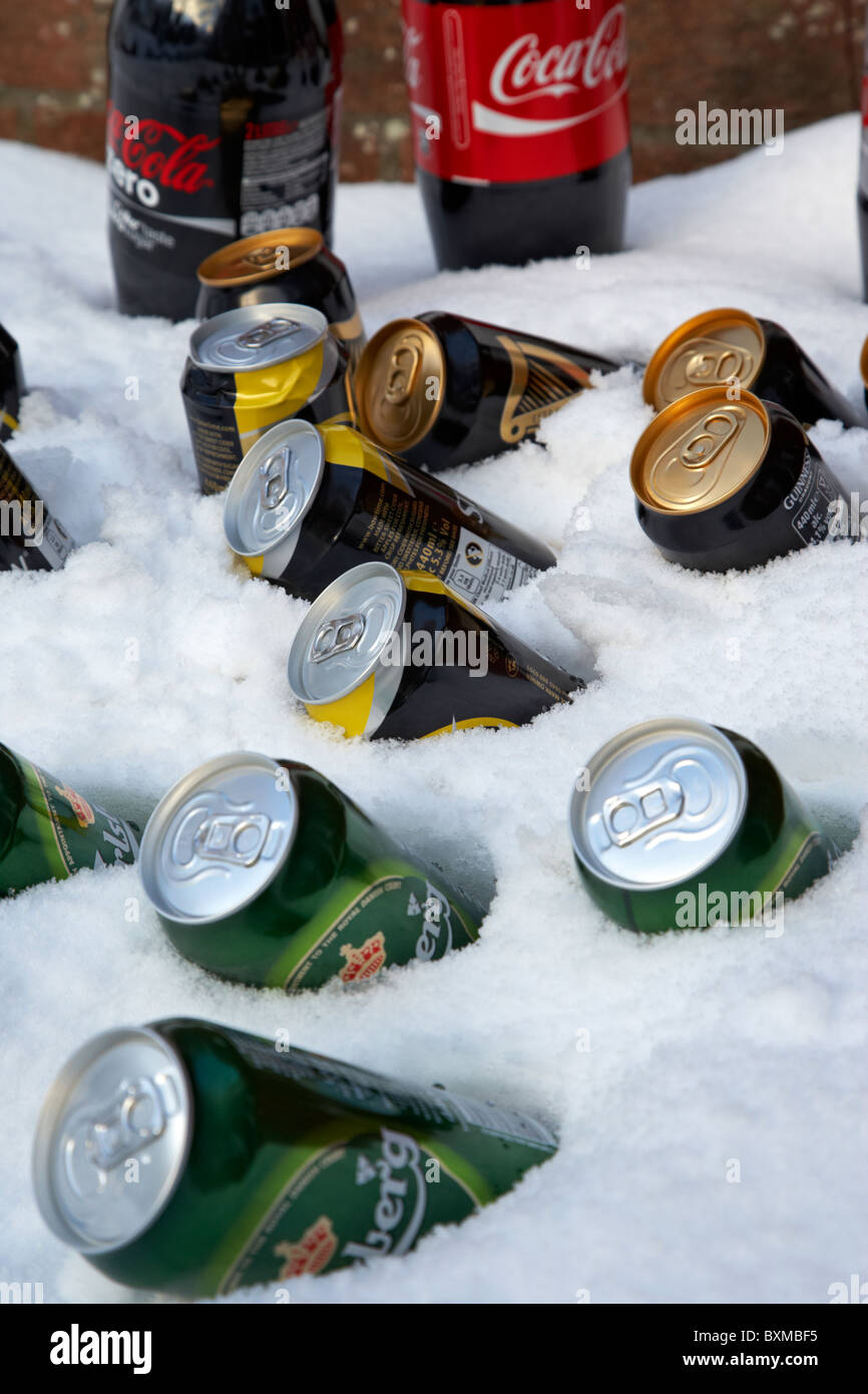 beer soft drinks and alcohol cans buried in snow to keep them cool outdoors during winter Stock Photo