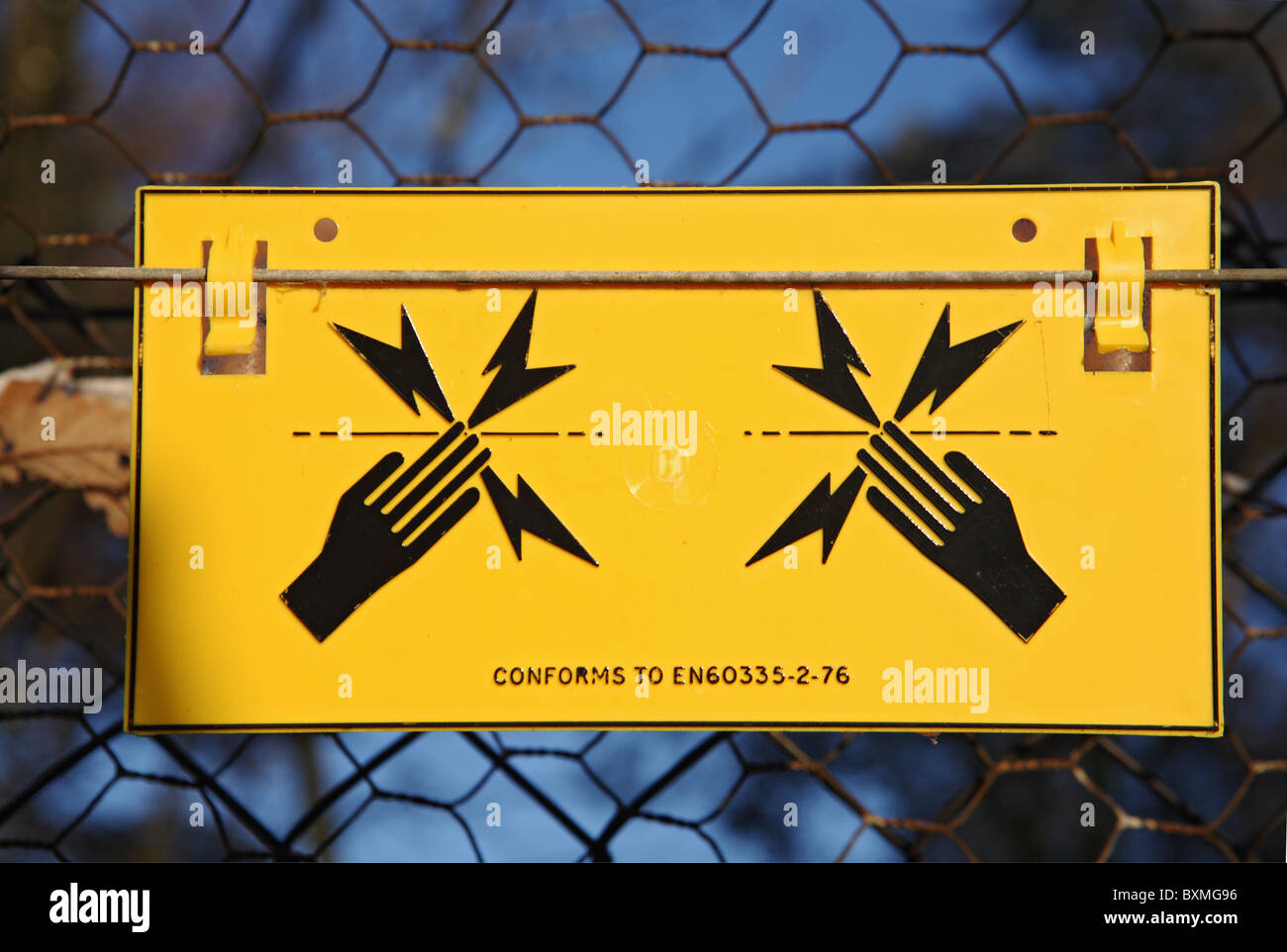 Sign warning of the danger of shock from an electrified boundary fence. England, UK Stock Photo