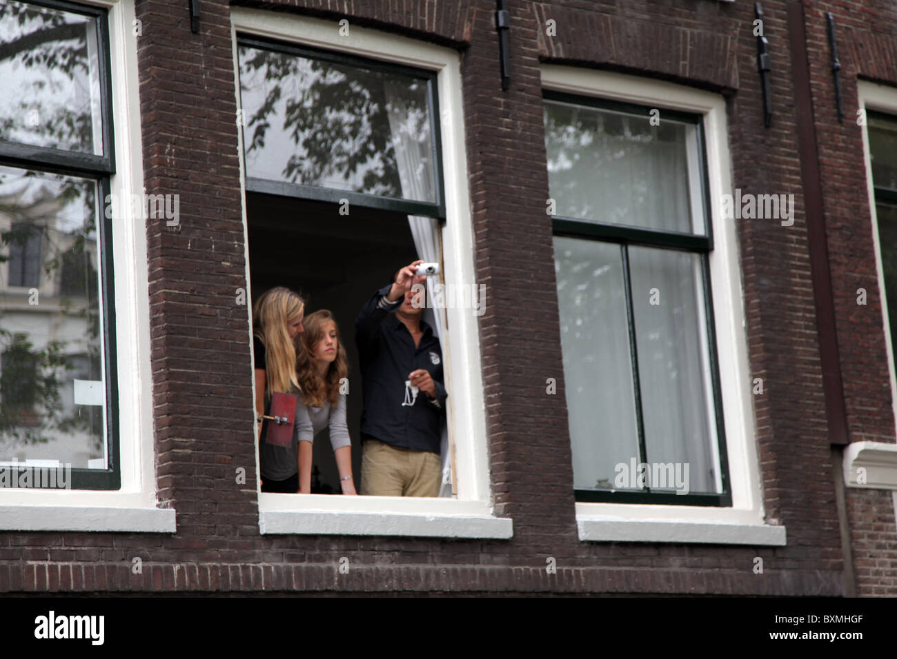 Family watching from a window during Gay Pride Amsterdam Stock Photo
