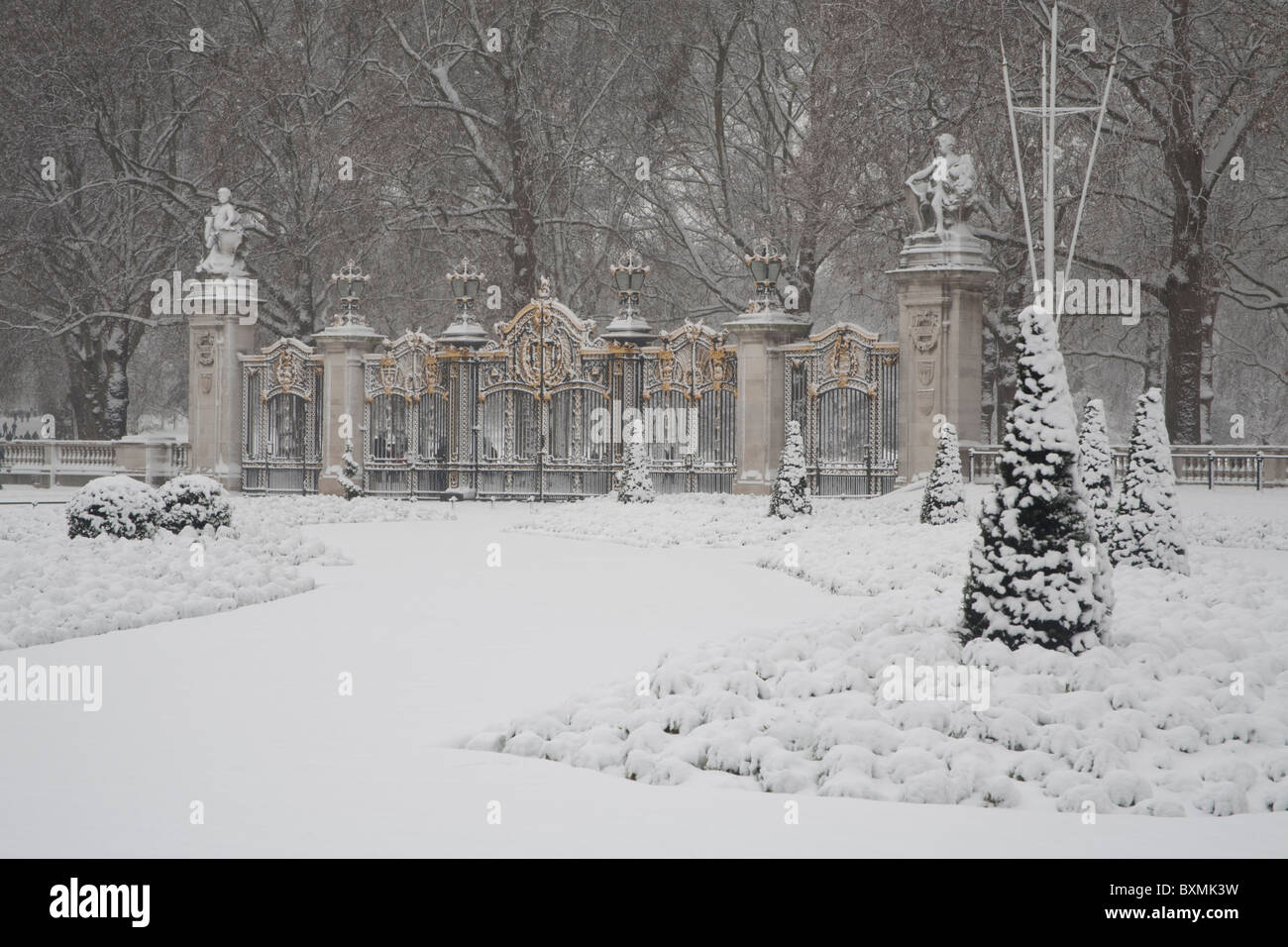 The beautifully ornate black and gold Canada Gate forming the 'Royal entrance' to Green Park in London during a heavy snow fall. Stock Photo