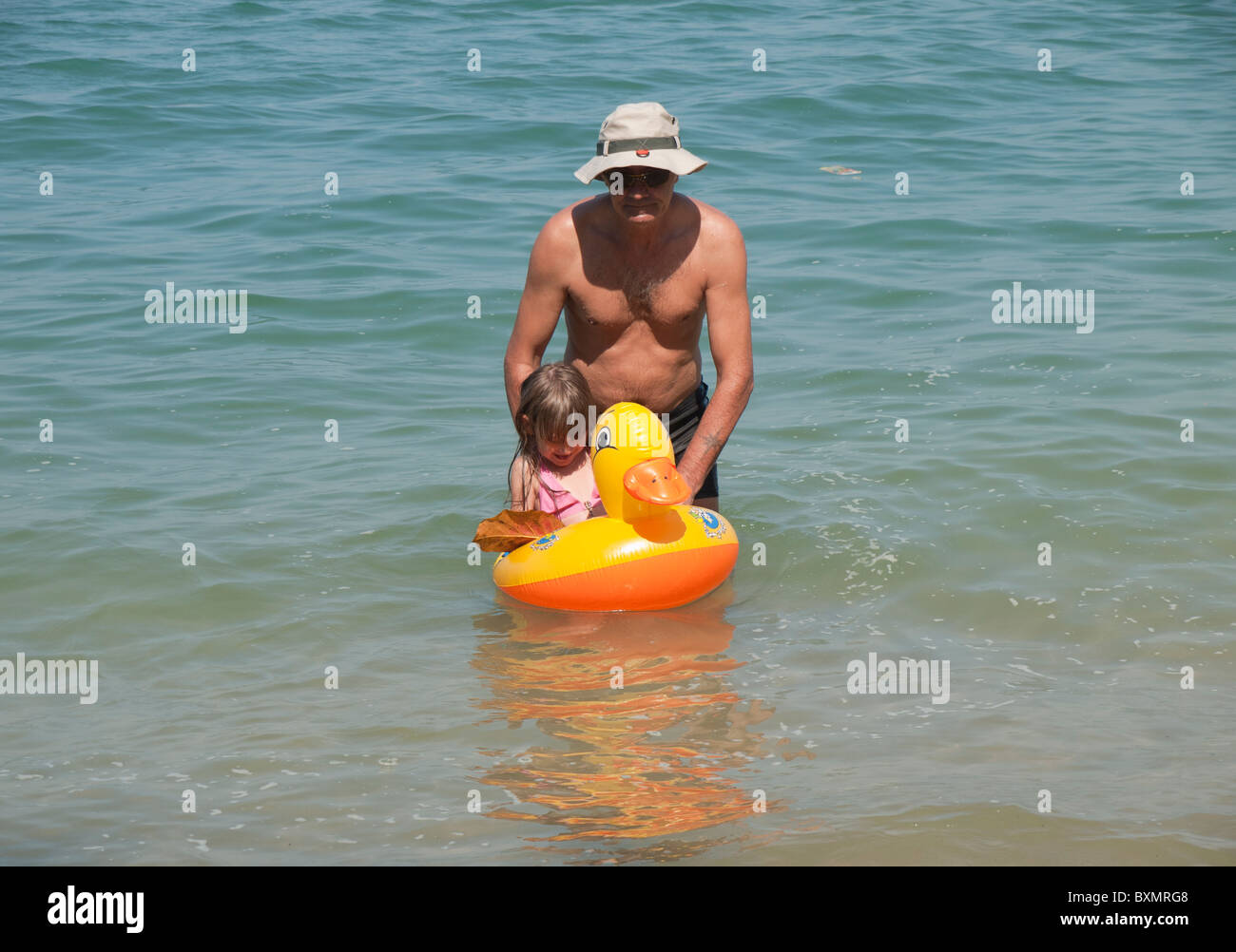 A girl on duck floating rubber ring with her father Stock Photo