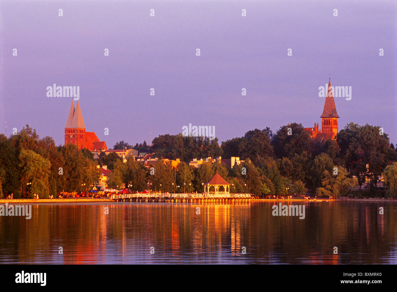 The Old Town of Ostroda with two brick churches across the Lake Drewenz glows in the warm evening light of a masurian summer. Stock Photo