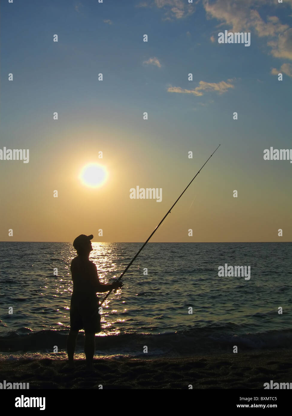 The silhouette of a fisherman on the beach at sunset Stock Photo