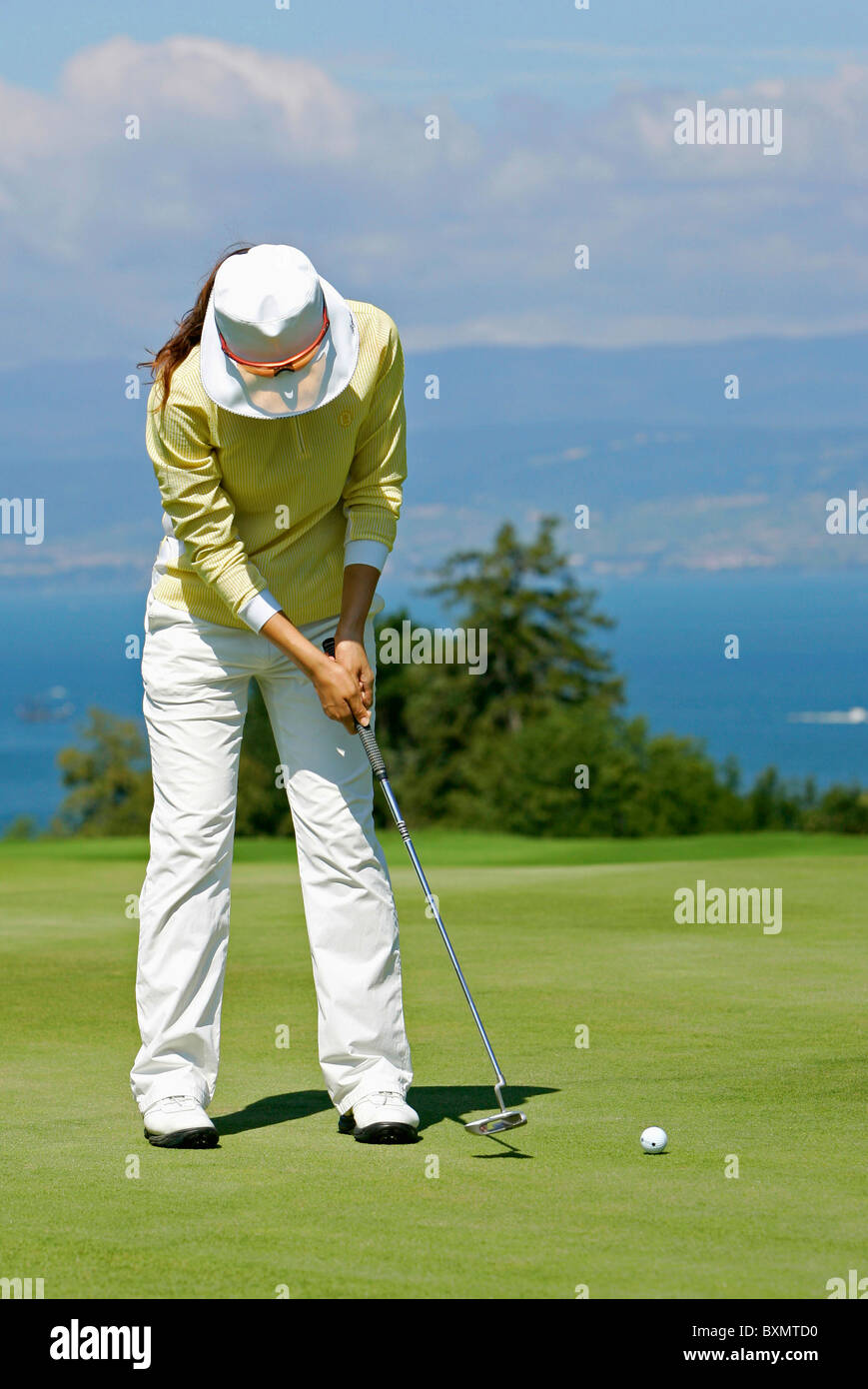 Woman with a sun hat  playing golf Stock Photo