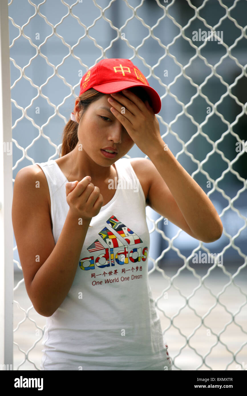 Female Chinese worker clutching head at Olympic Games, Beijing, China Stock Photo
