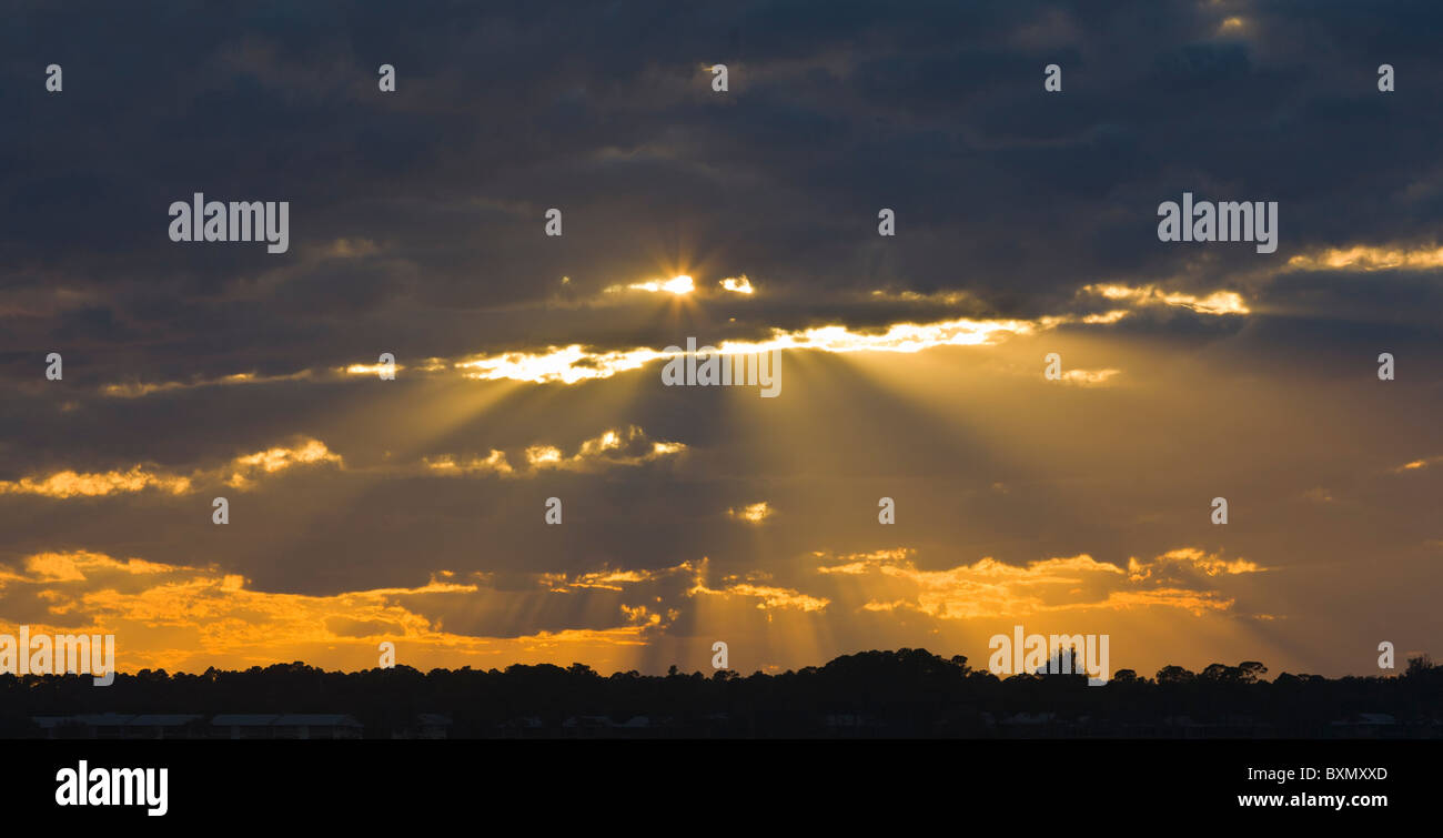 God rays though dark clouds with orange sky below Stock Photo