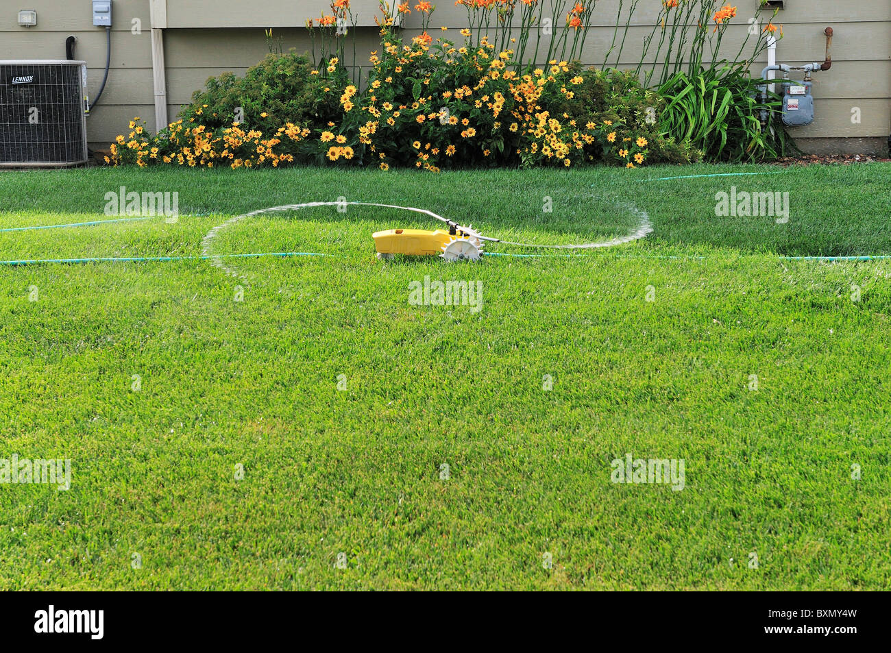 A traveling tractor lawn sprinkler waters a lawn in Wichita, Kansas, USA. Stock Photo
