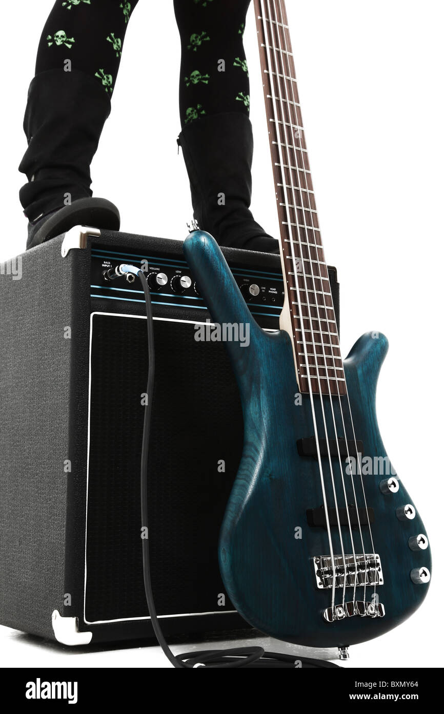 Amp and 5 string bass guitar over white with female boots legs standing on amp. Stock Photo
