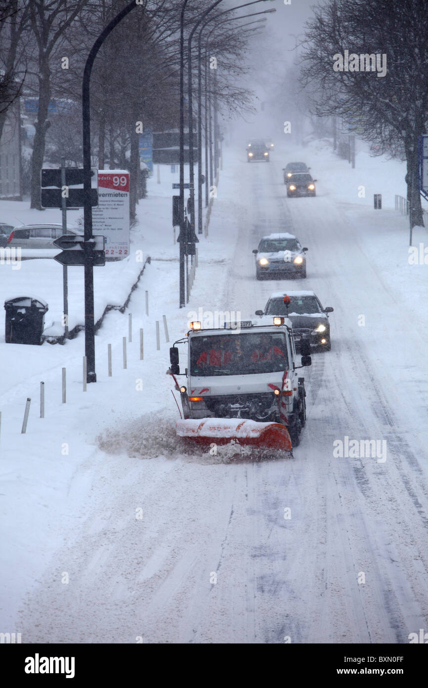 Wintertime, traffic in a city center, snow covered streets. Street and walkway cleaning, snowplough in action. Stock Photo