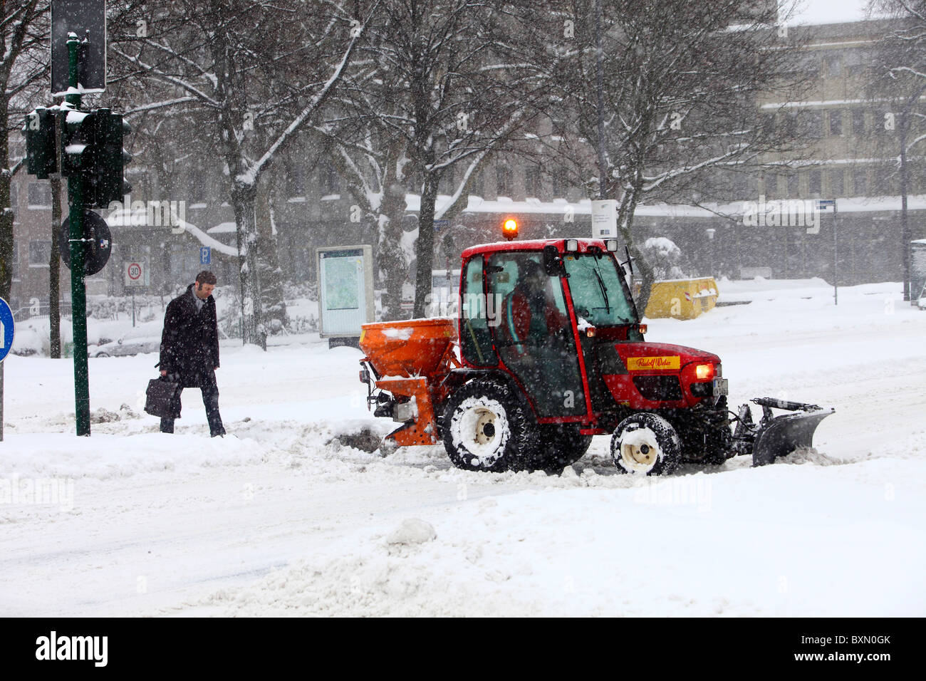 Wintertime, traffic in a city center, snow covered streets. Street and walkway cleaning, snowplough in action. Stock Photo