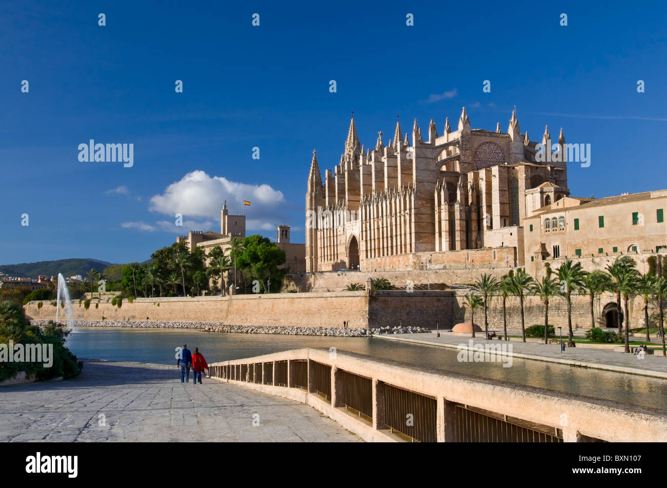 Palma Cathedral and Parc de la Mar sea inlet with tourist couple standing looking at magnificent vista Mallorca Balearics Spain Stock Photo