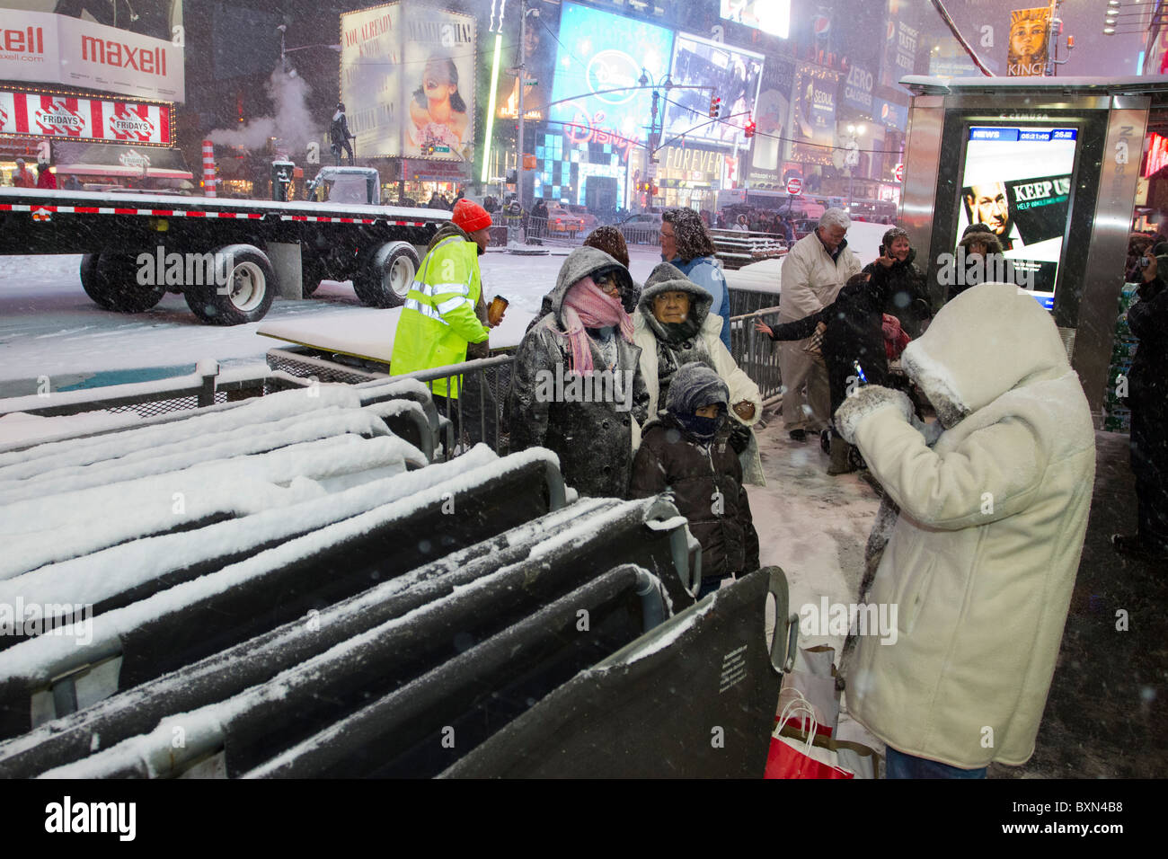 Visitors to Times Square have their photo taken next to workers who are preparing for the New Year's celebration there. Stock Photo