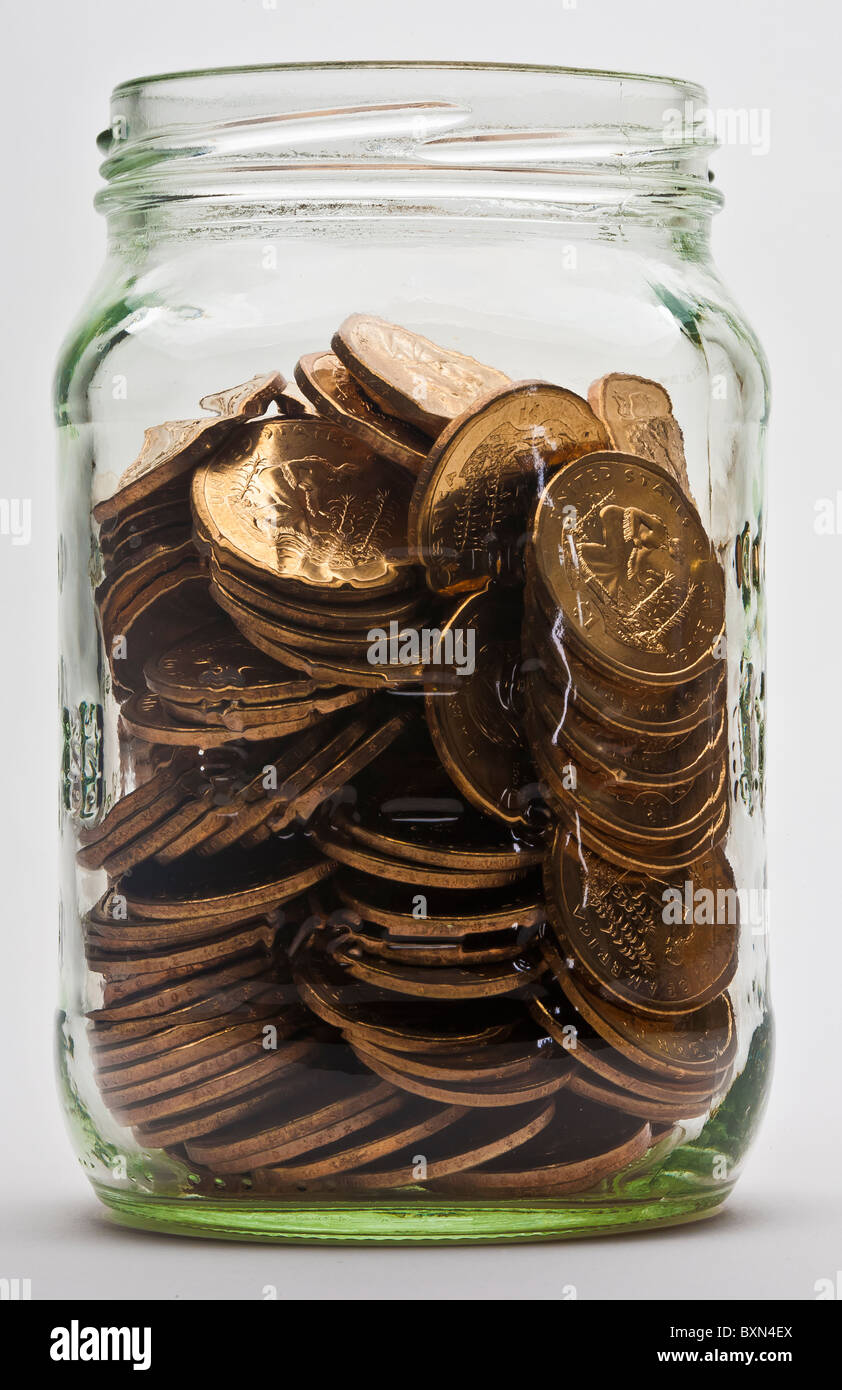 three-quarter full jar of US dollar gold coins Stock Photo