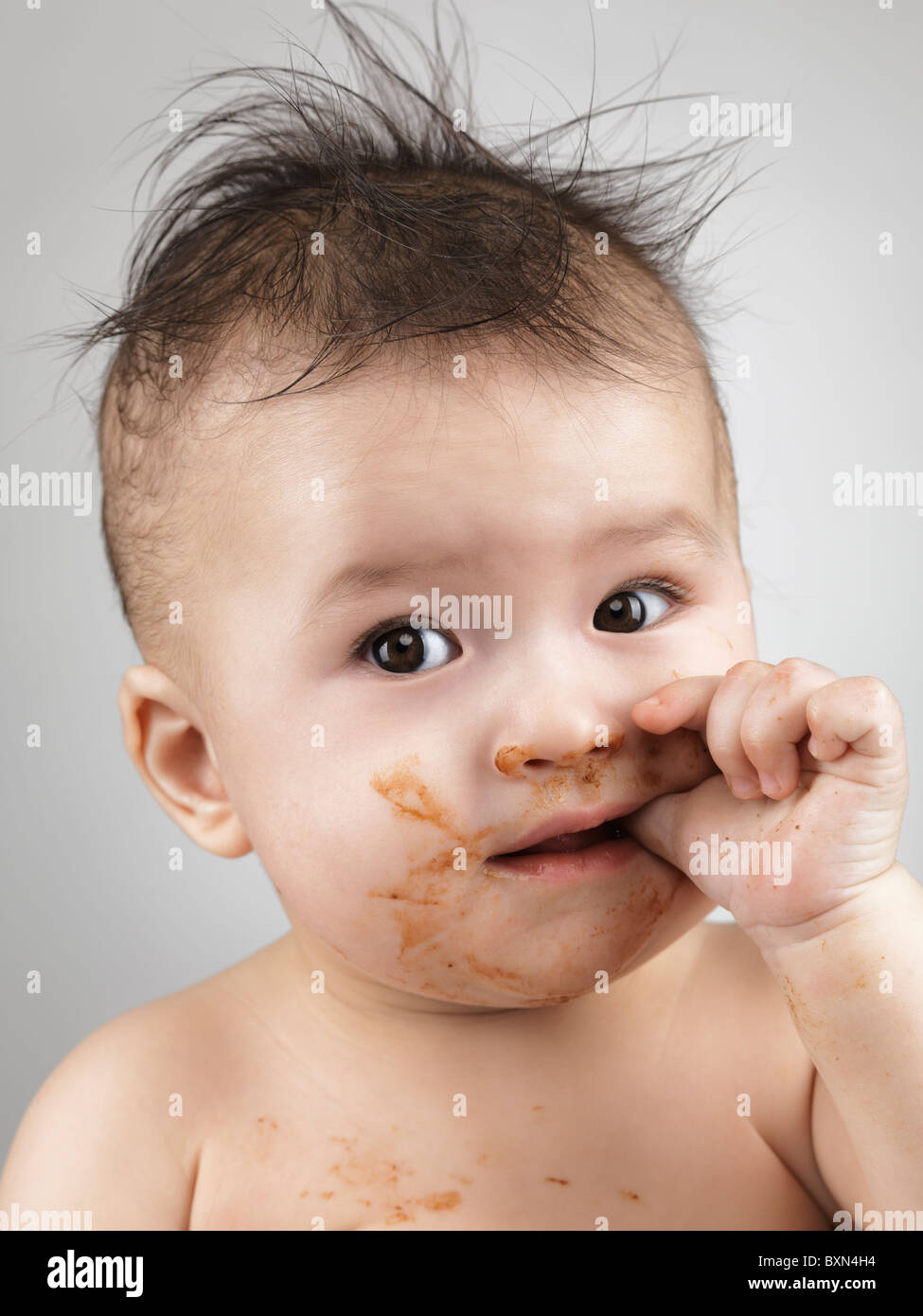 License available at MaximImages.com - Artistic portrait of a seven month old baby boy with messy hair and smudged with food face sucking his thumb Stock Photo