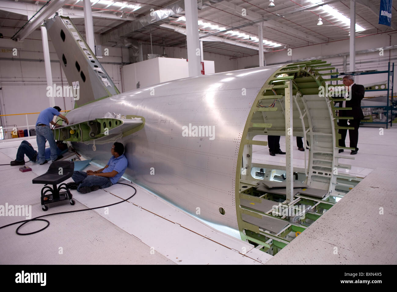 Workers build part of the structure of a plane in a Bombardier