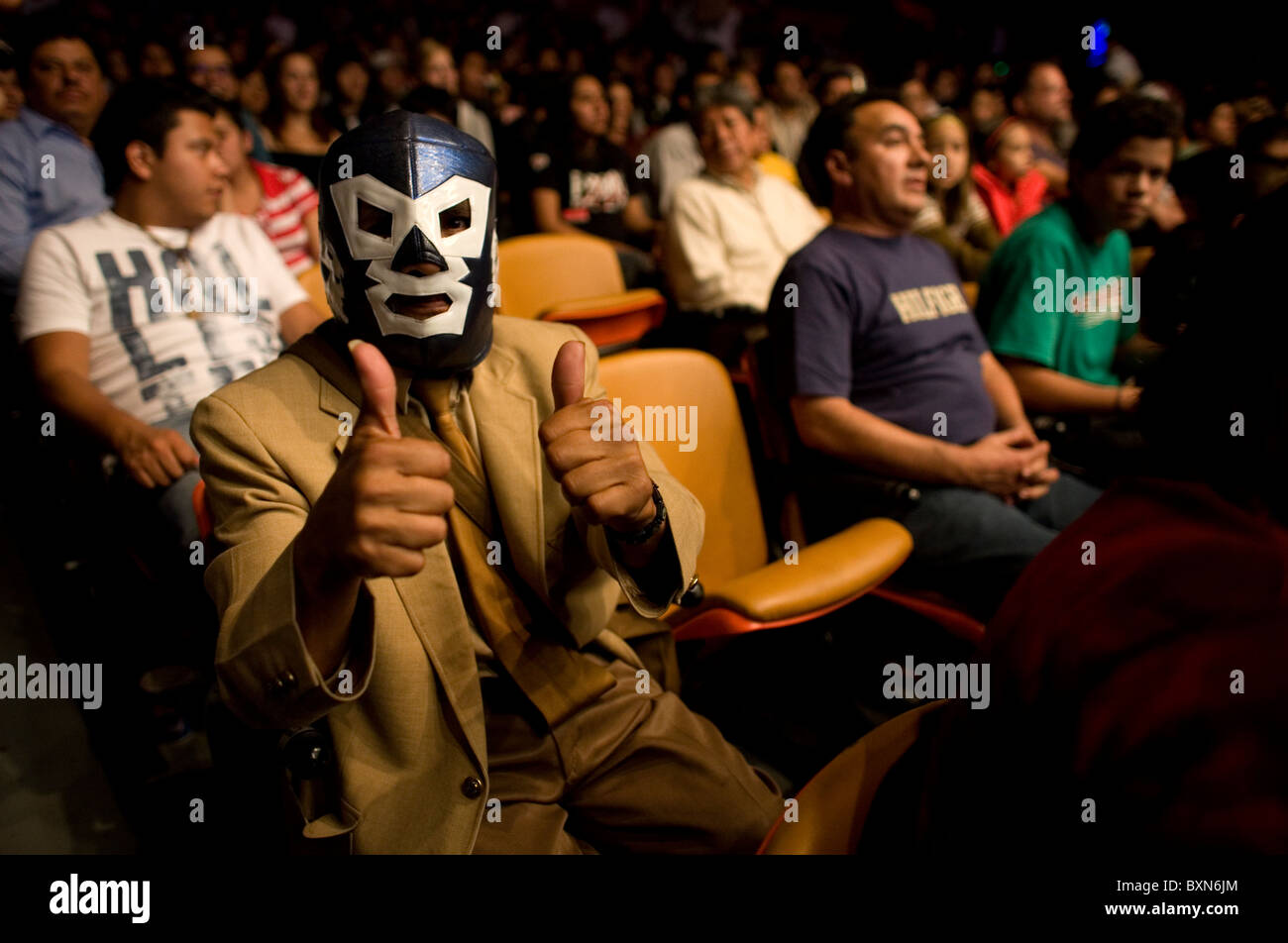 A fan wearing a Lucha Libre mask give the thumbs up as he watches a wrestling fight in Arena Mexico, Mexico City Stock Photo