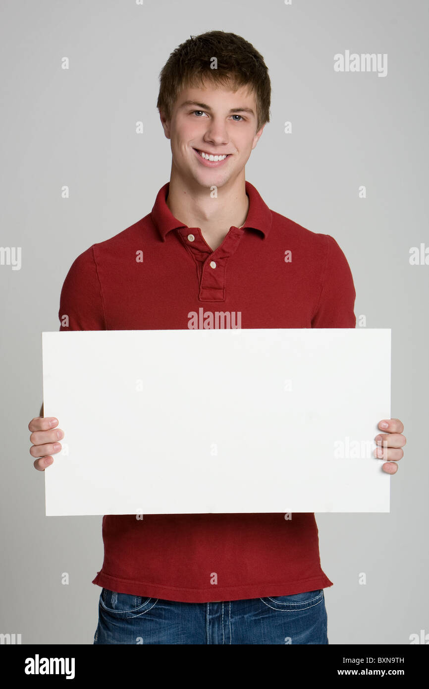 Attractive teenage boy holding a blank sign isolated on white ...