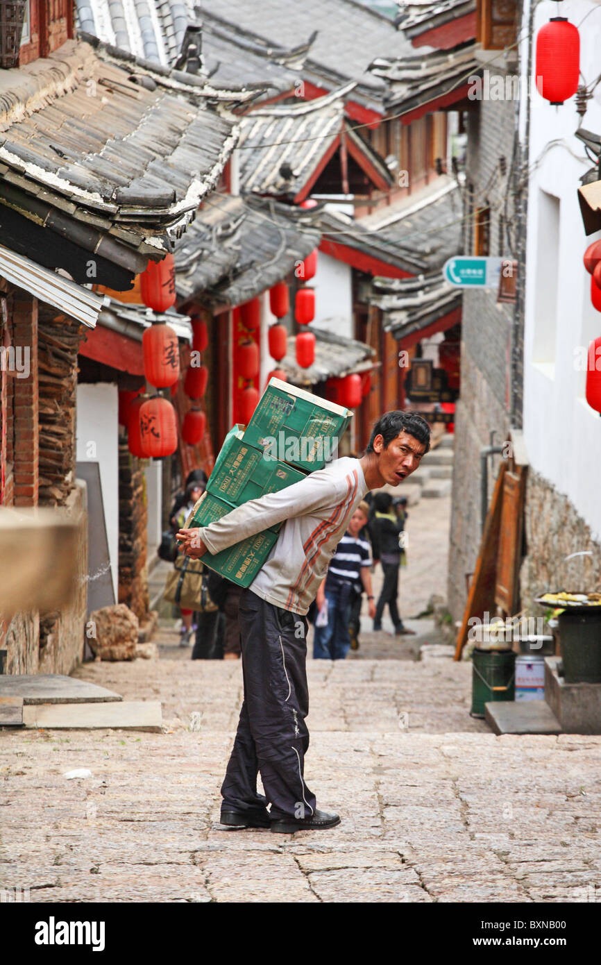 Man carrying heavy boxes in Lijiang, Yunnan Province, China Stock Photo