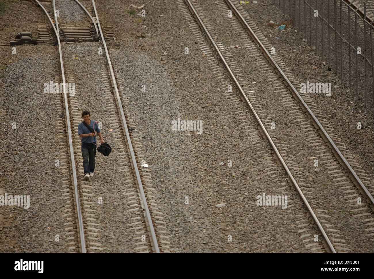 A Central American migrant traveling across Mexico to work in the United States walks along a railroad track in Mexico City Stock Photo