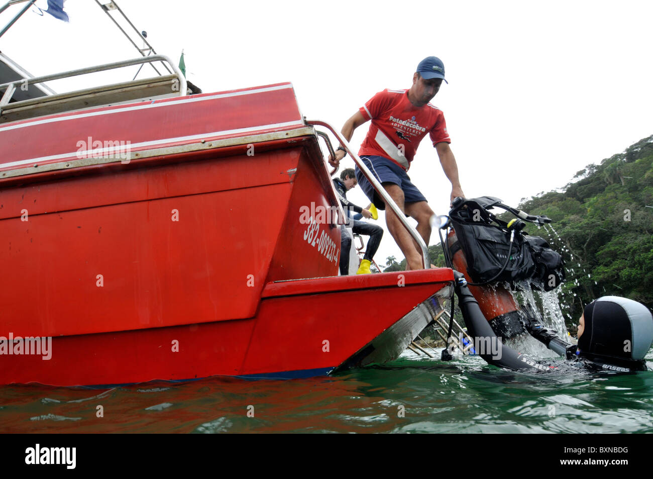 Staff picks up gear as divers return to dive boat, Bombinhas, Santa Catarina, Brazil Stock Photo