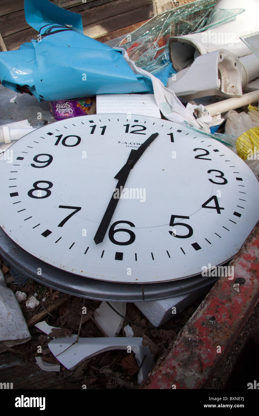 A large clock face with the hands at 12:31 on a pile of rubbish. Stock Photo