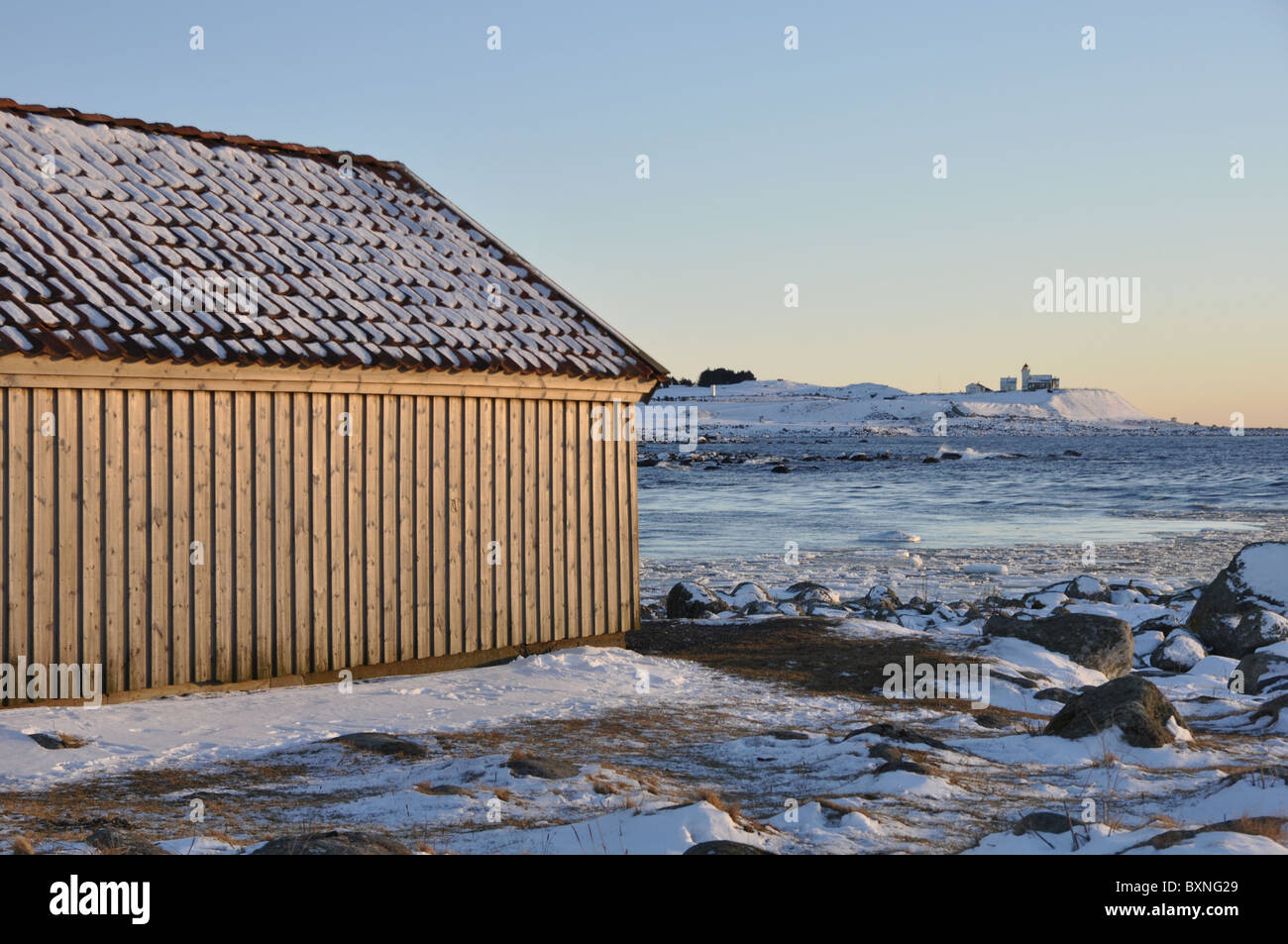 Where river meets the sea, winter, low sun, snow, boat houses, light house Stock Photo