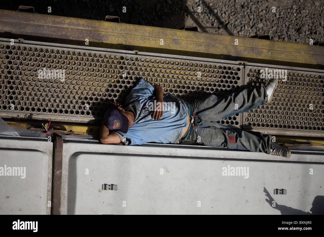 A Central American migrant traveling across Mexico to work in the United States lies on the roof of a cargo train in Mexico City Stock Photo
