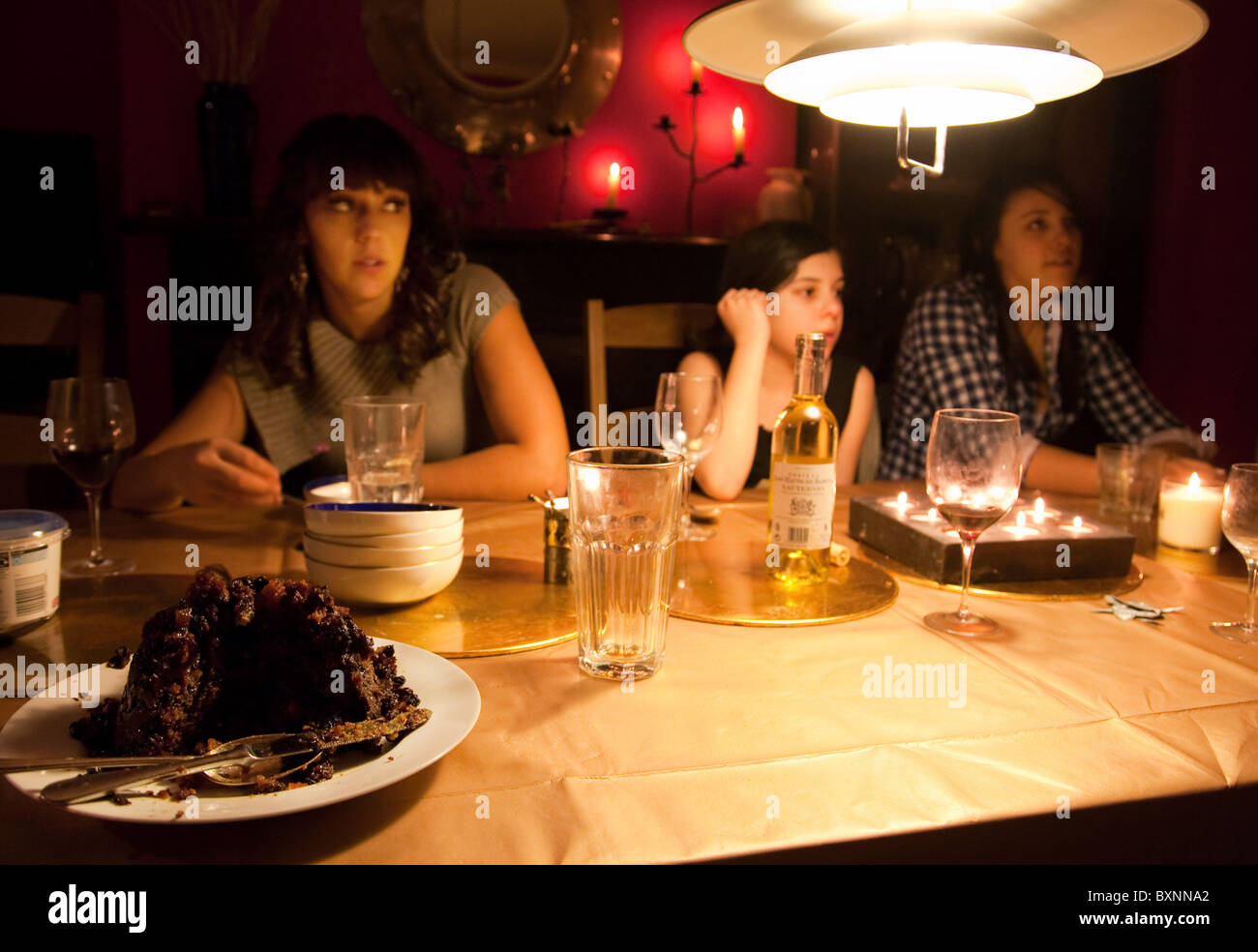Three children at the christmas dinner table with christmas pudding, london UK Stock Photo