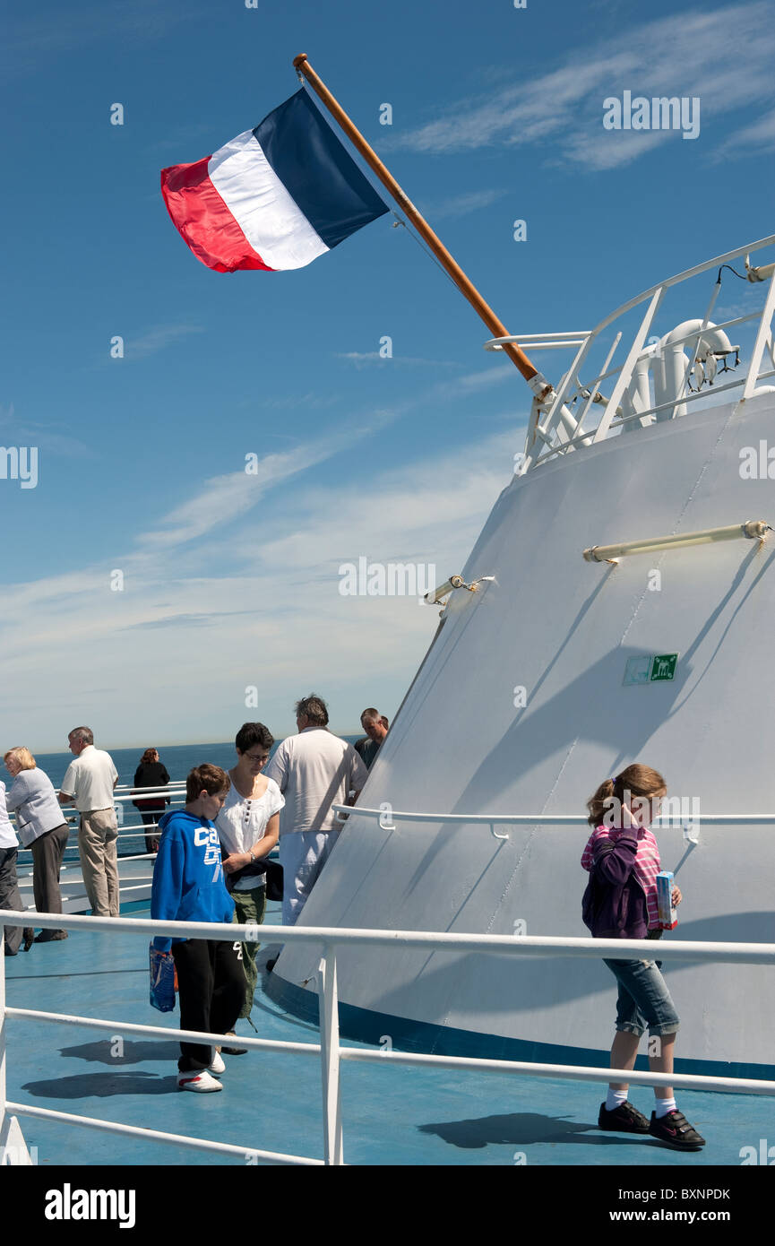 People on Ferry with French Flag Flying against Blue Sky Stock Photo