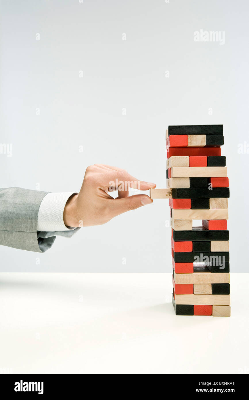 Businessman hand removing block from tower of blocks Stock Photo - Alamy