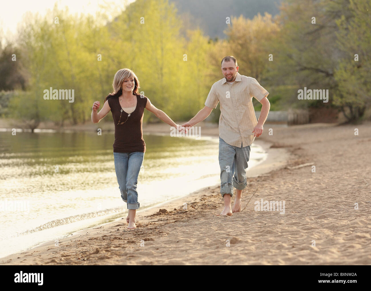 cute young Caucasian couple running on beach holding hands Stock Photo ...