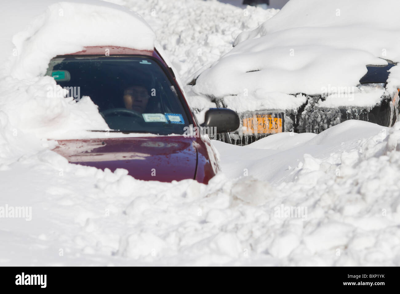 A woman sitting in her snowbound car the day after a blizzard dumped ...