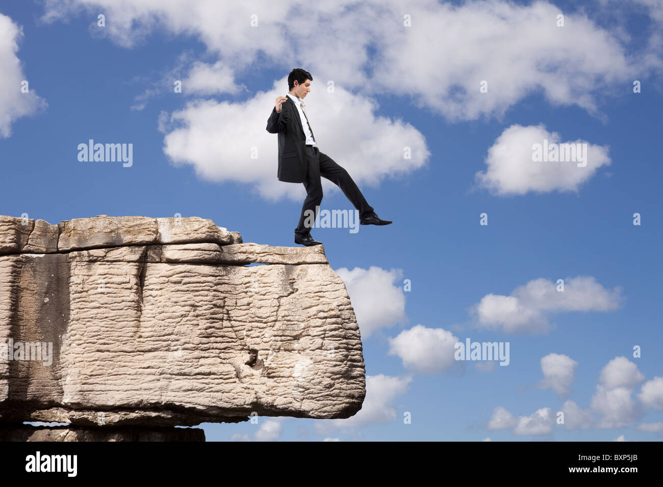 Businessman making a danger and step falling from a rock Stock Photo