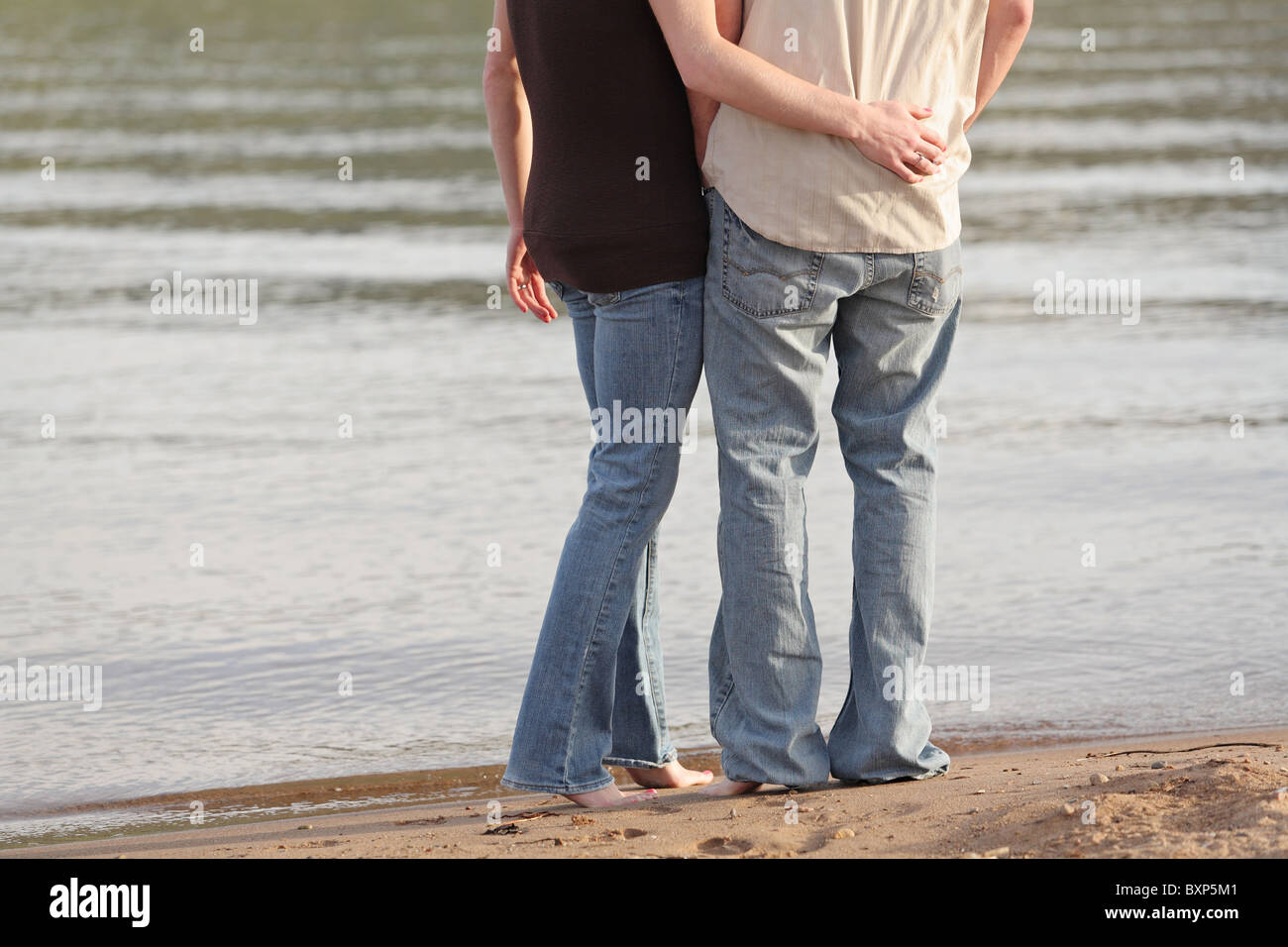 young couple in casual dress standing together near lake edge Stock Photo -  Alamy