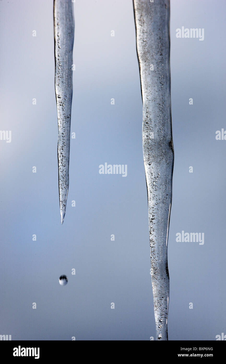 Large icicles hanging in front of a window, down from the roof. Wintertime. Stock Photo