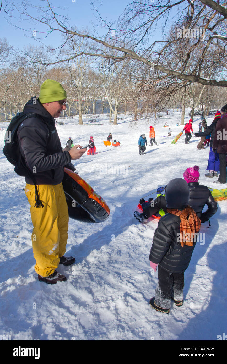 A boy waits for this father to finish texting so he can go sledding in