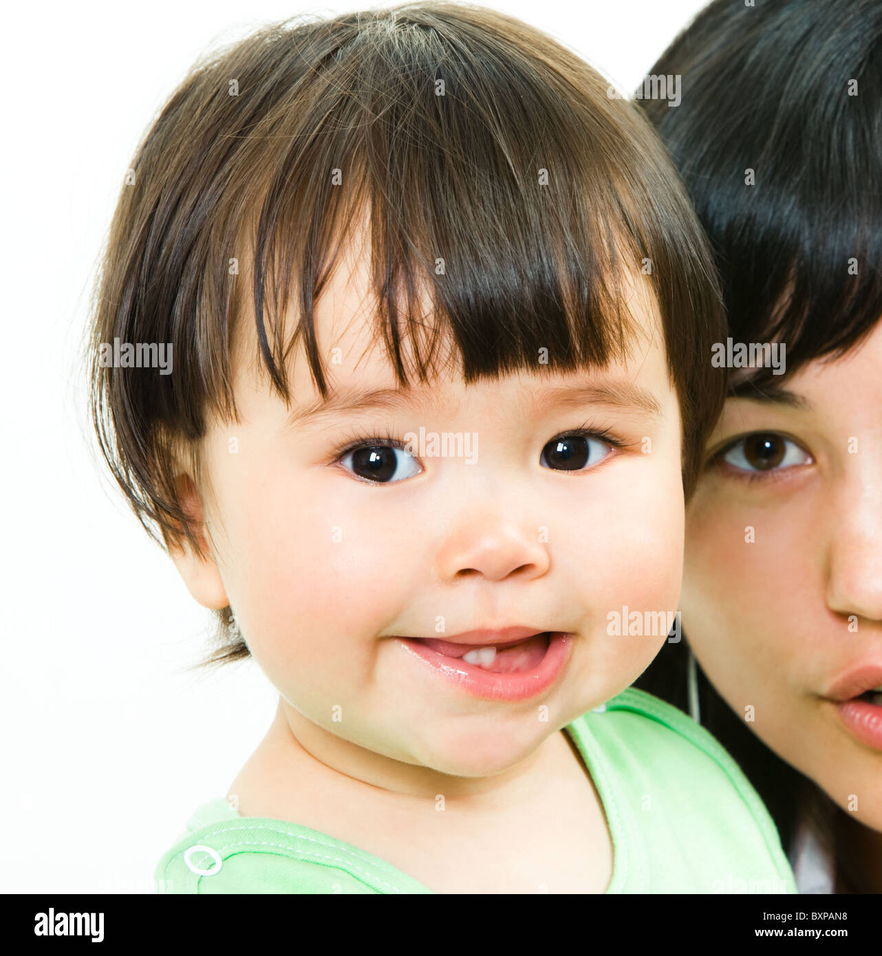 Close-up of small girl’s face looking at camera with her mother on the background Stock Photo