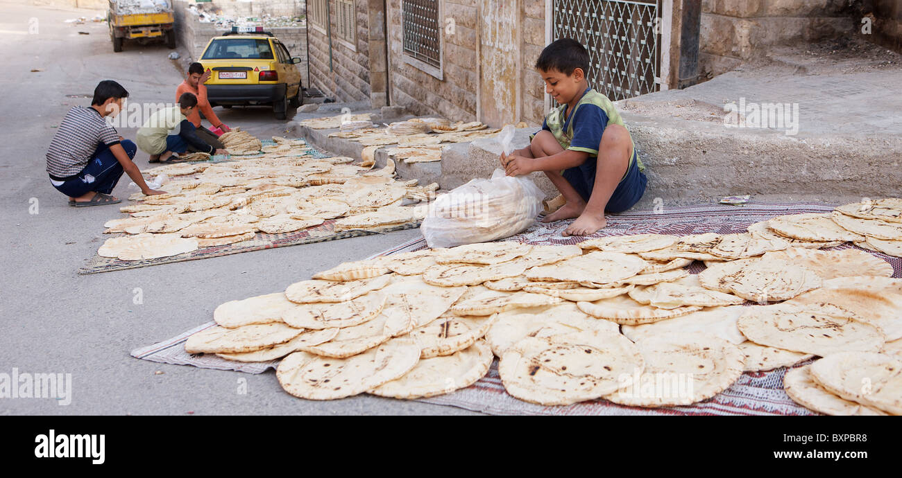 Drying freshly-baked flatbreads on the pavement outside a backstreet bakery in Hama, Syria Stock Photo