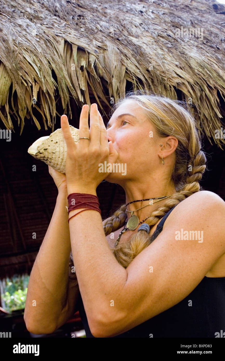 Woman Blowing Through A Conch Shell Stock Photo