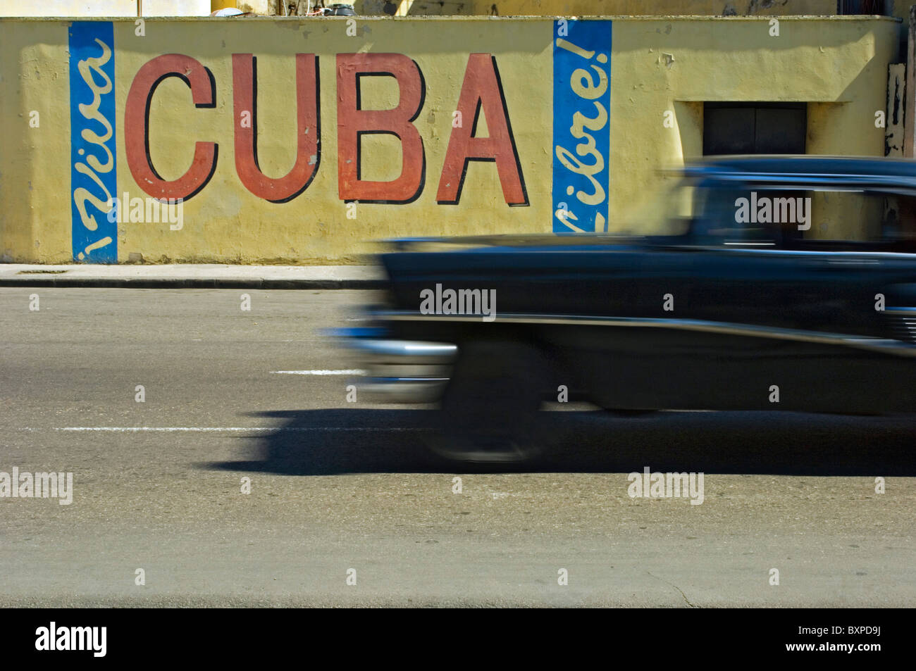 A Blurred Classic Car Passes A Viva Cuba Sign. Stock Photo