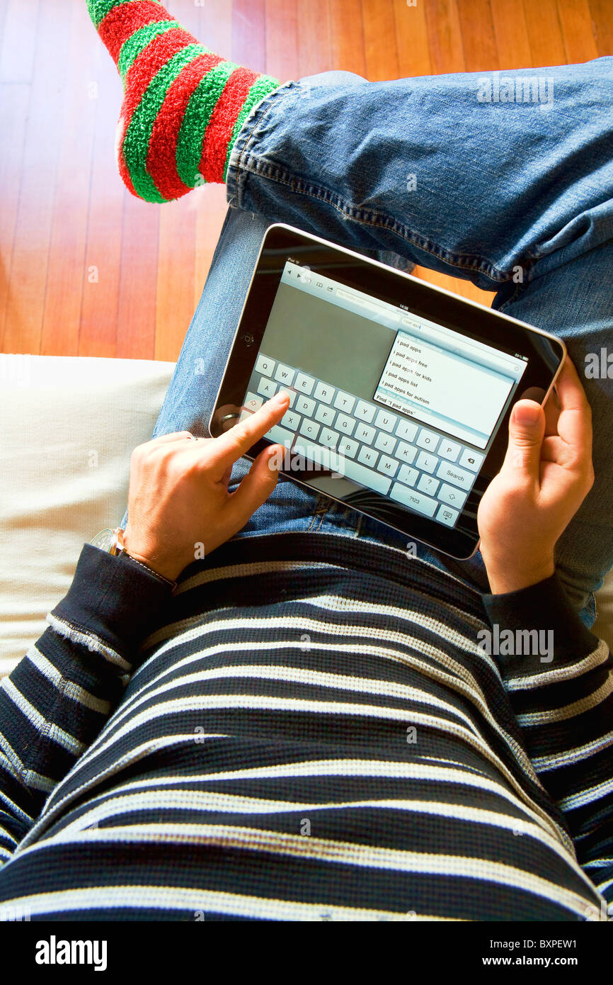 Man using an Apple iPad on his lap typing into a search engine Stock Photo