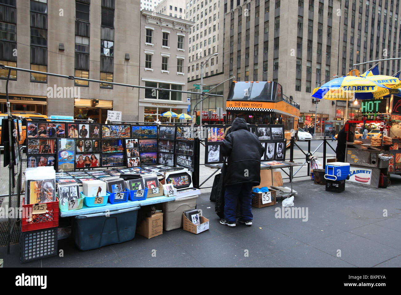 A taxi-tours bus cruises by a tradesman selling tourist photographs on Sixth Avenue of New York city in Christmas 2010 Stock Photo