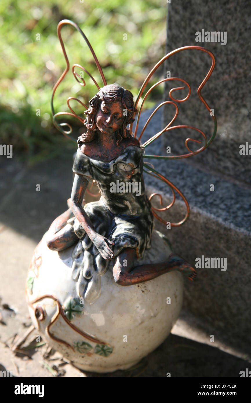 A broken winged angel figurine sat on a grave Stock Photo