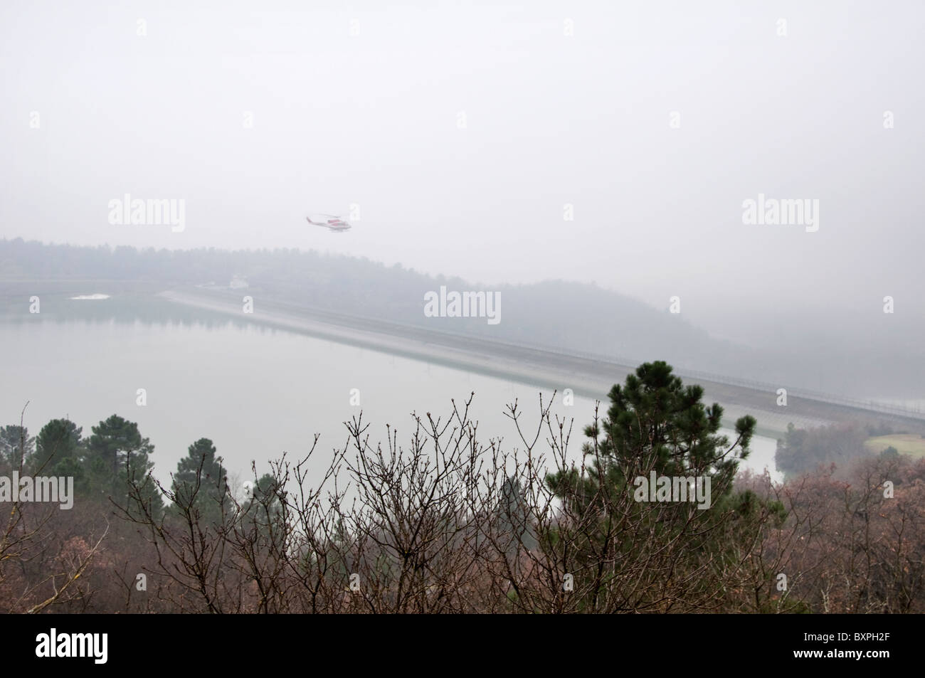 Helicopter in fog over Montedoglio Dam burst with a 30 metre gap in the wall, 29 Dec, 2010, near Sansepolcro. Stock Photo